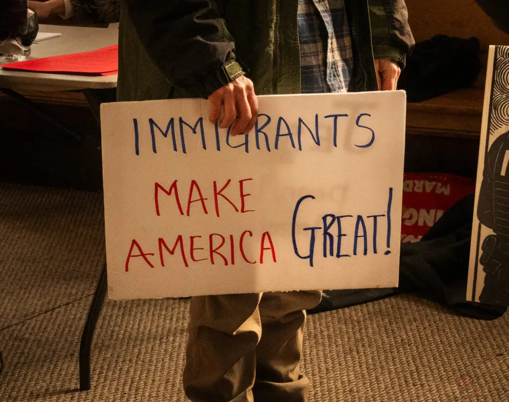 Community member holding sign "IMMIGRANTS MAKE AMERICA GREAT!"